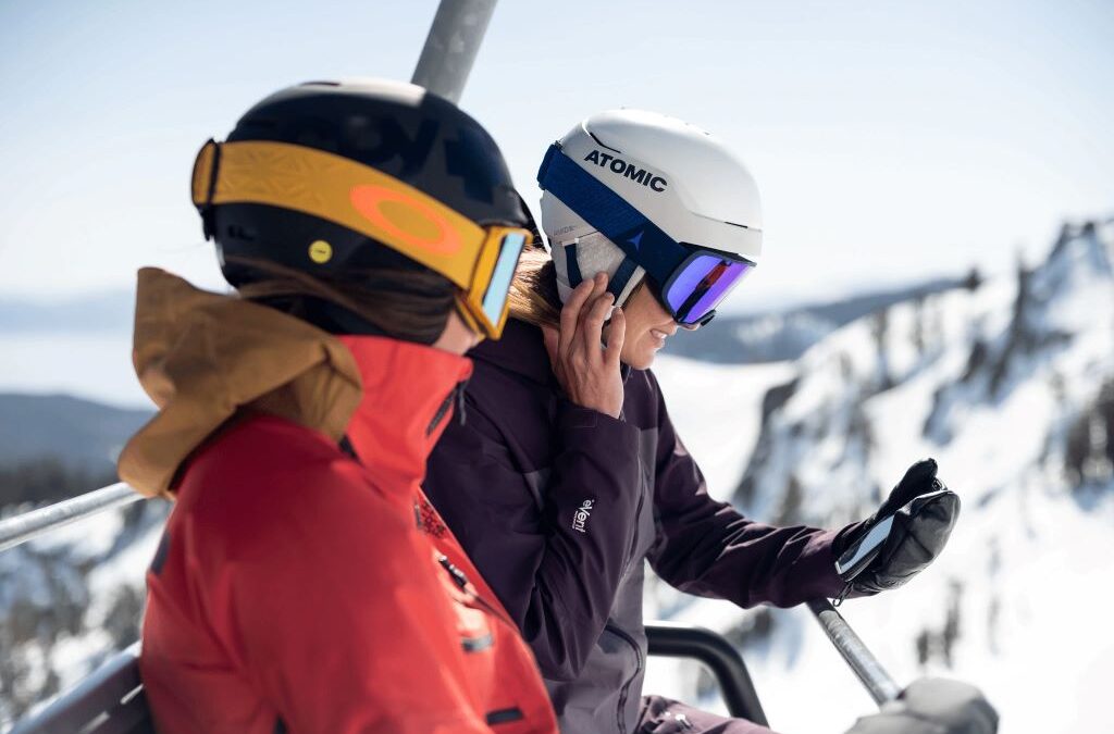 A snowboarder wearing a Smith Vantage helmet smiles on a chairlift while listening to music through integrated helmet audio