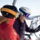 A snowboarder wearing a Smith Vantage helmet smiles on a chairlift while listening to music through integrated helmet audio