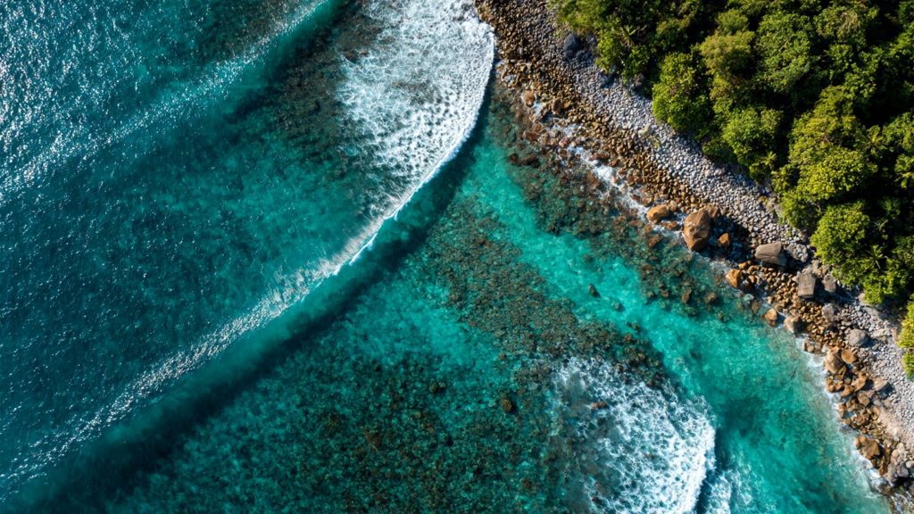 2. Aerial view of hidden surf spot showing turquoise water breaking over reef with rocky coastline and no crowds