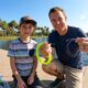 Parent teaching child an easy braid to fluoro fishing knot beside an Orlando lake during a weekend trip