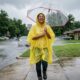 Person wearing a budget yellow rain poncho smiling during a Texas downpour.